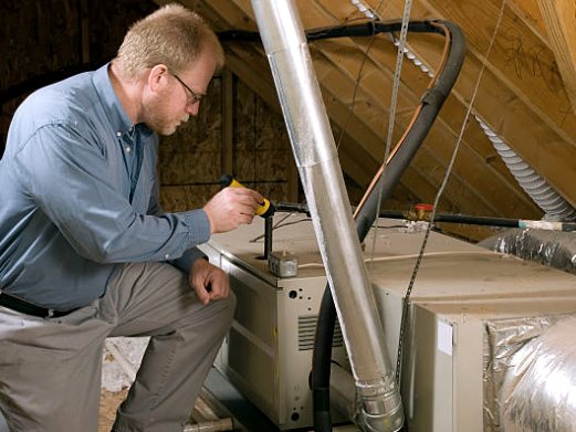 Technician working on a furnace and ductwork in an attic